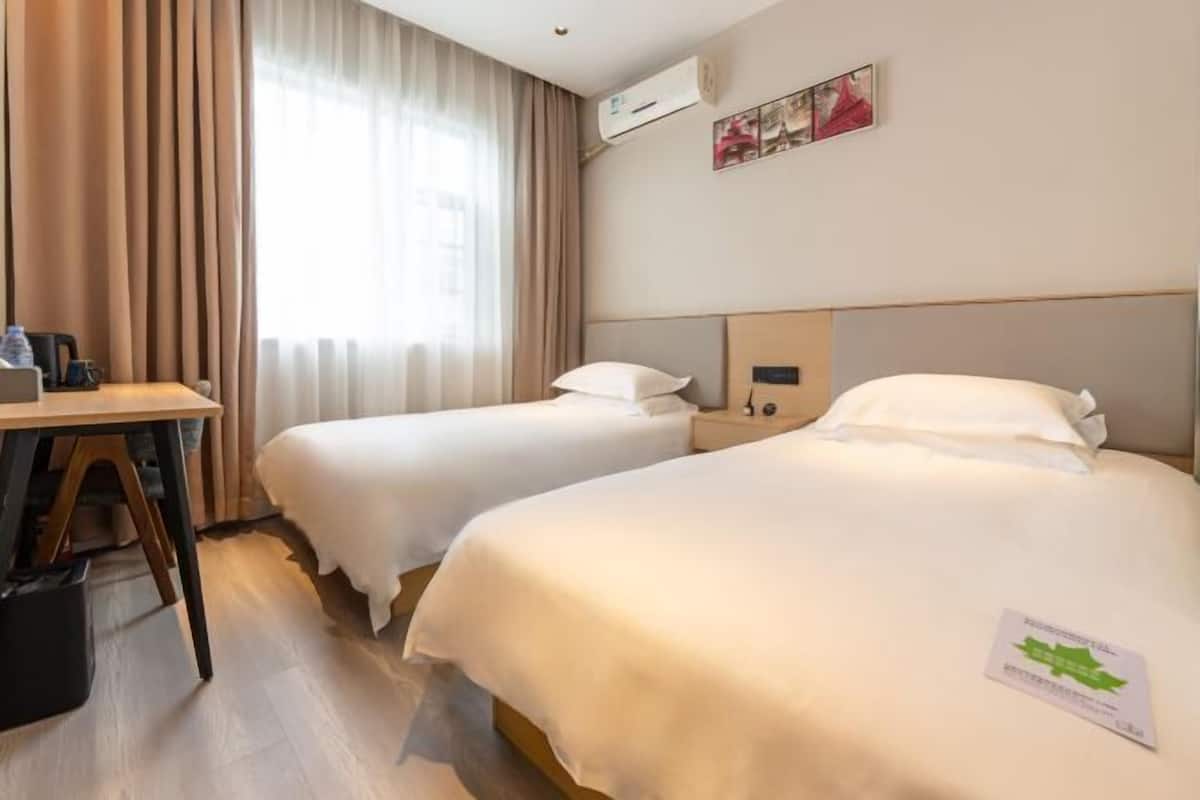 Una habitación de hotel con dos camas, un escritorio y una ventana con cortinas.