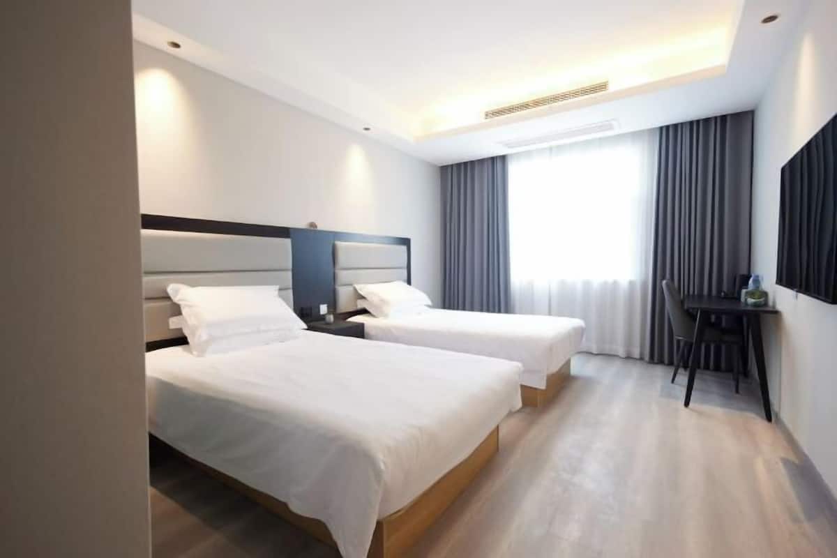 Una habitación de hotel con dos camas, un escritorio y una silla.