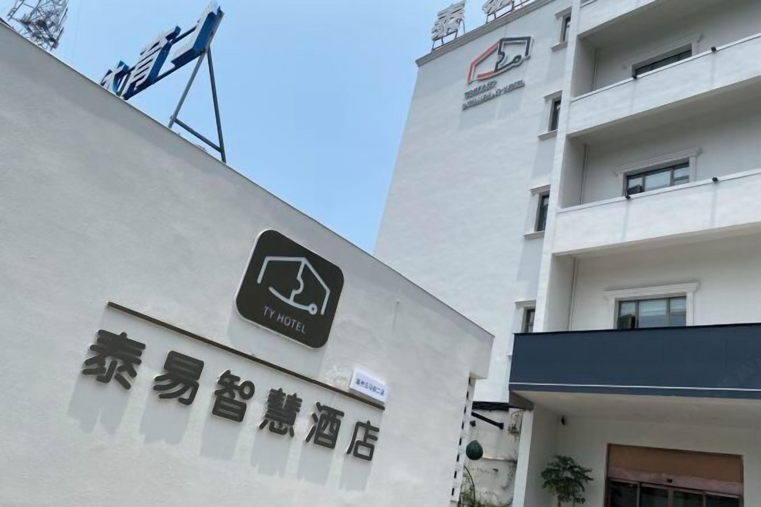 A TY Hotel sign on a building with a modern design, featuring a logo and Chinese characters.