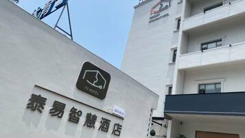 A TY Hotel sign on a building with a modern design, featuring a logo and Chinese characters.