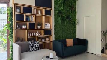 Una sala de estar con un sofá, una mesa de centro, una estantería y una pared verde.