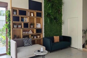 A living room with a sofa, a coffee table, a bookshelf, and a green wall. - Wenzhou Taiyi Smart Hotel (Jingshan Park General Bridge Branch) (Wenzhou)