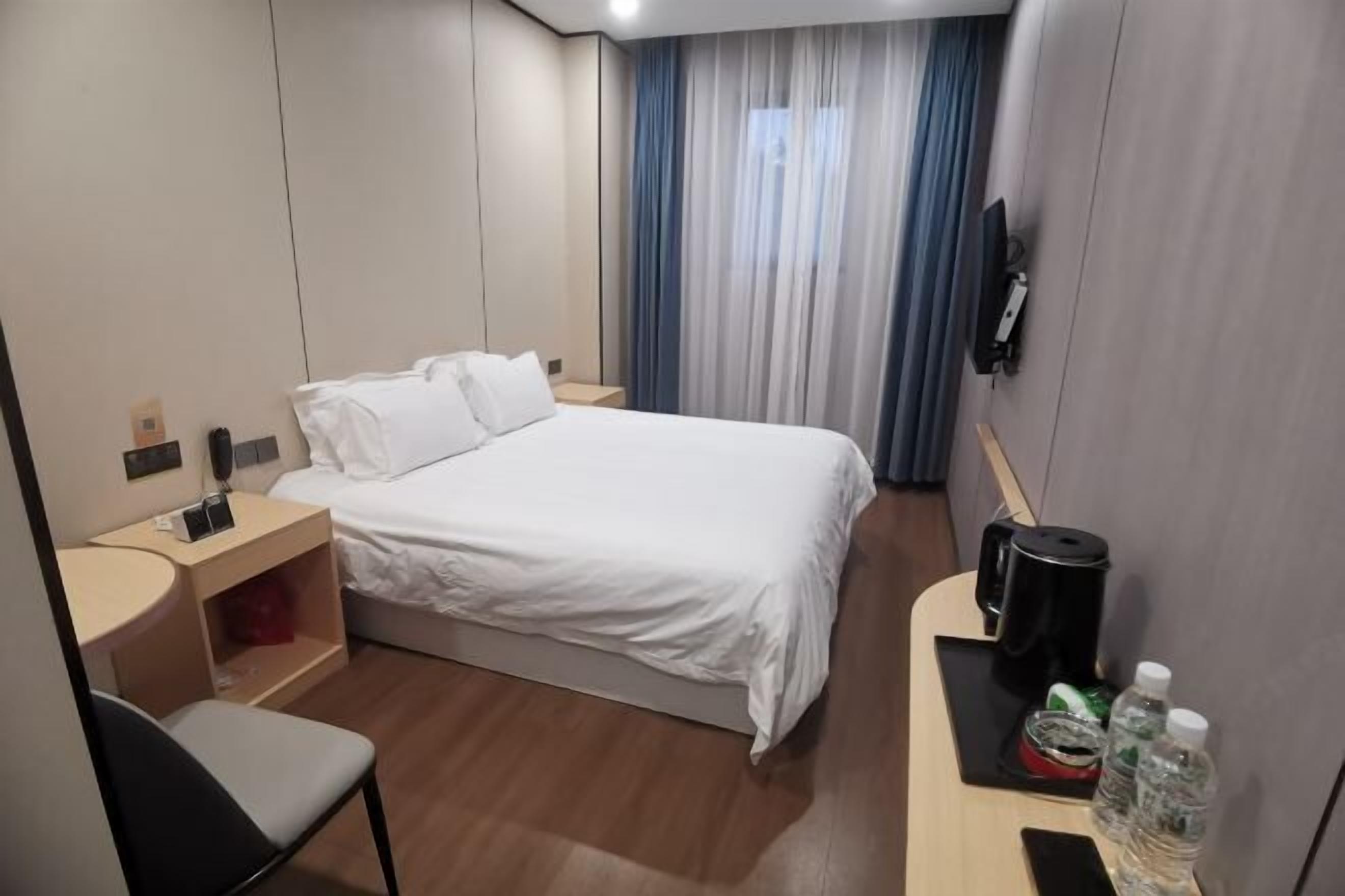 Une chambre d’hôtel avec un lit, un bureau doté d’une machine à café, une chaise et un téléviseur fixé au mur.