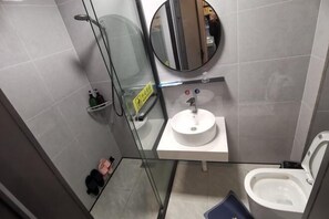 A modern bathroom with a glass shower enclosure, a round mirror, a white sink, and a toilet. - Wenzhou Taiyi Smart Hotel (Jingshan Park General Bridge Branch) (Wenzhou)
