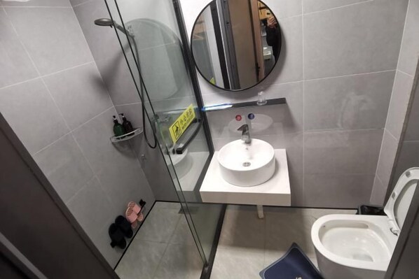 A modern bathroom with a glass shower enclosure, a round mirror, a white sink, and a toilet. - Wenzhou Taiyi Smart Hotel (Jingshan Park General Bridge Branch) (Wenzhou)