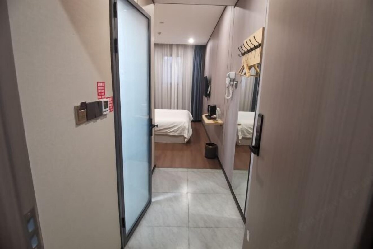 A hotel room with a bed, a desk, a telephone, and a mirror.