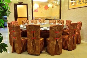 Un salón de conferencias con una mesa redonda y sillas, algunas con corbatas rojas.