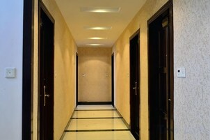 Un pasillo con puertas a ambos lados, suelo de baldosas e iluminación empotrada en el techo.