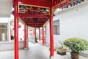 A covered walkway with red pillars and a potted plant.