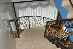 Una escalera de caracol con barandillas de metal ornamentadas y una vista despejada del cielo.