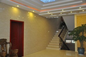 A modern interior with a staircase, a red door, and a potted plant. - Q+ Jiuhuashan Hongyunlou Grand Hotel (Qingyang)