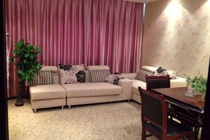 Una sala de estar con un sofá color beige, una mesa de comedor y una planta en maceta.