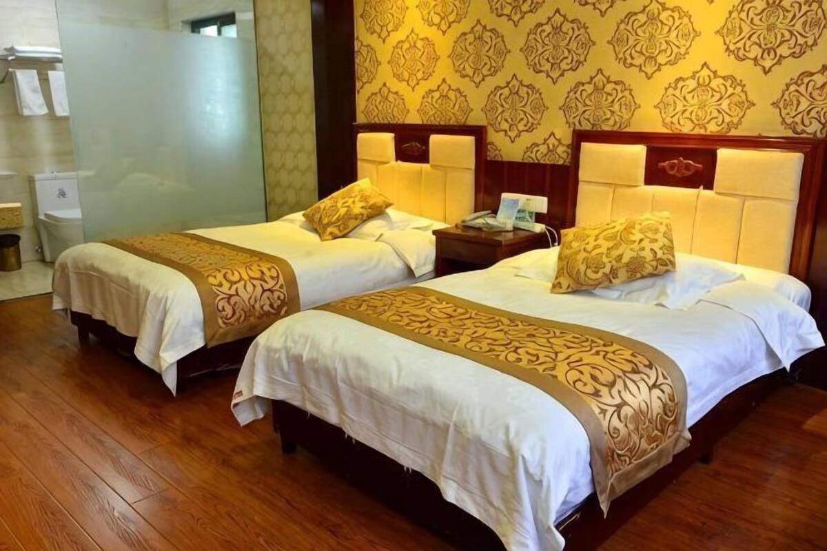 Une chambre d’hôtel avec deux lits, un plancher en bois et un papier peint à motifs.