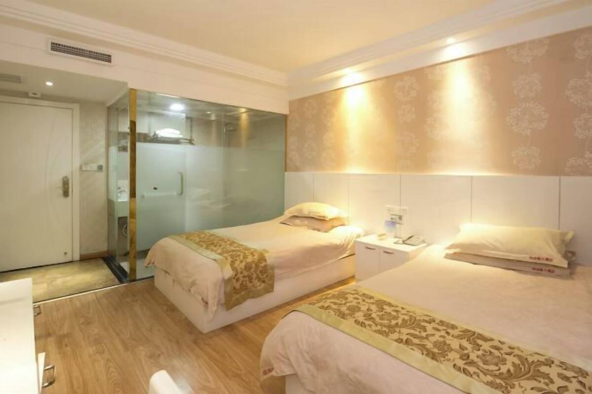 Une chambre d’hôtel avec deux lits, une table de chevet avec une lampe, un miroir et une armoire.