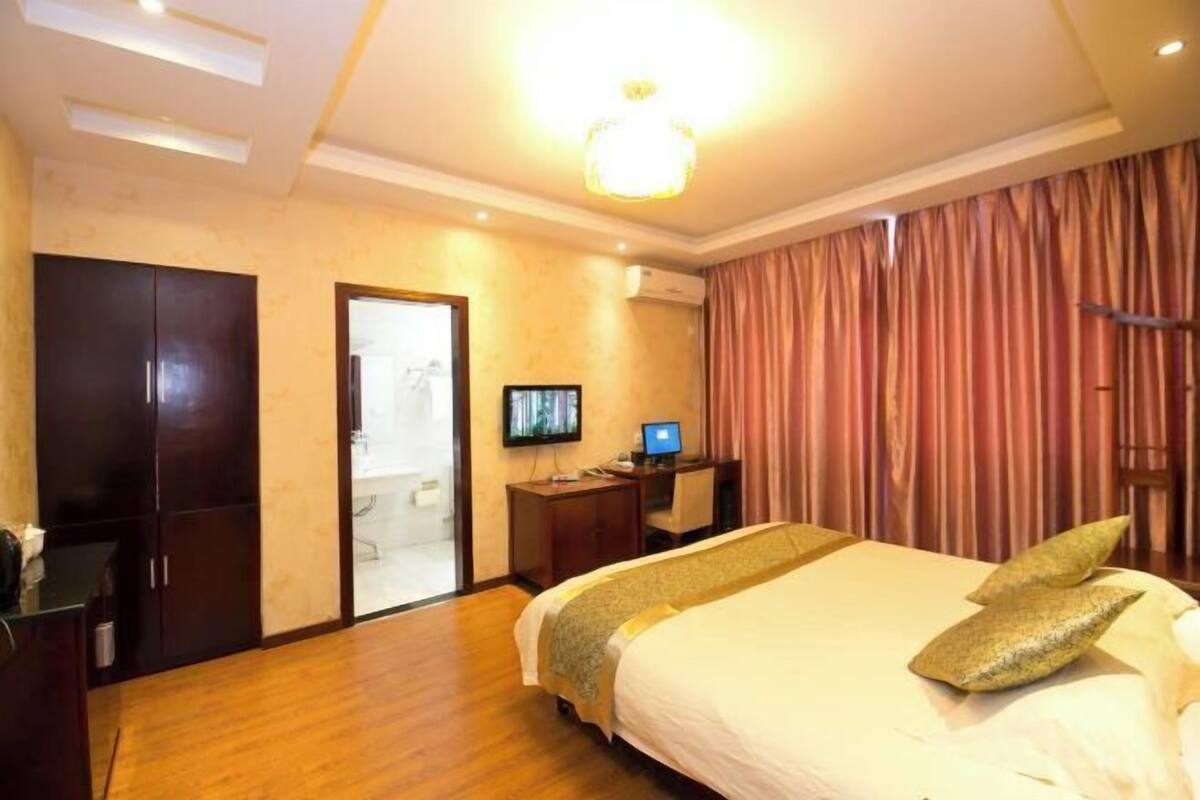 Une chambre d’hôtel comprenant un lit, un bureau avec un ordinateur, une télévision et une armoire.