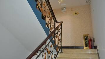 Una escalera con barandales de metal decorados y una pared color crema.