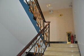 A staircase with ornate metal railings and a beige wall.