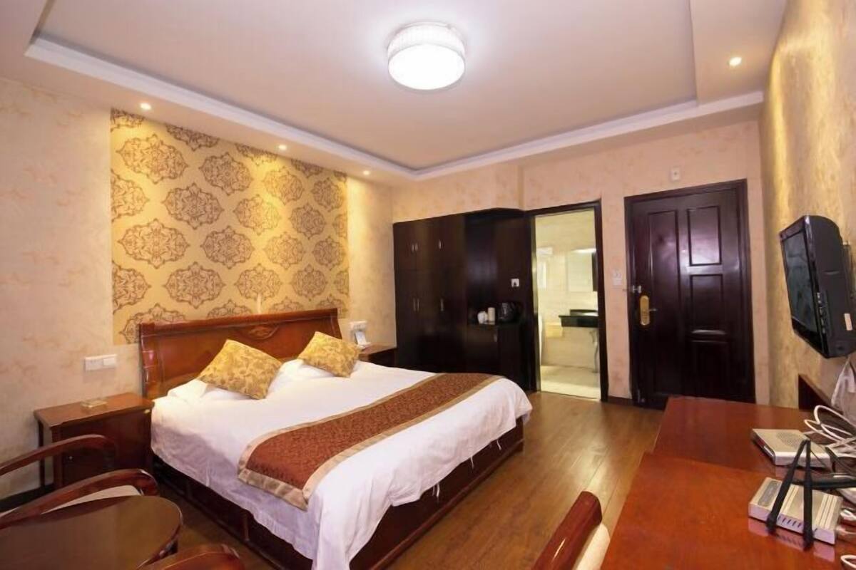 Une chambre d’hôtel comprenant un lit, un bureau, une chaise, une armoire et un téléviseur.