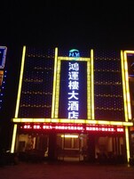 Fachada de hotel con señalización iluminada y estructura definida.