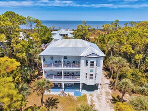 A two-story building with a balcony, surrounded by trees and a view of the water. - Because you deserve the best! (St George Island)