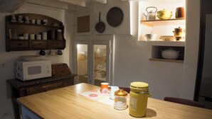 A kitchen with wooden cabinets, a microwave, a wooden table, and various kitchen utensils. - Nice rustico with see view (Canal D'oro)