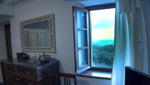 A room with a wooden dresser, a mirror, and a window with a view of a forested area. - Nice rustico with see view (Canal D'oro)