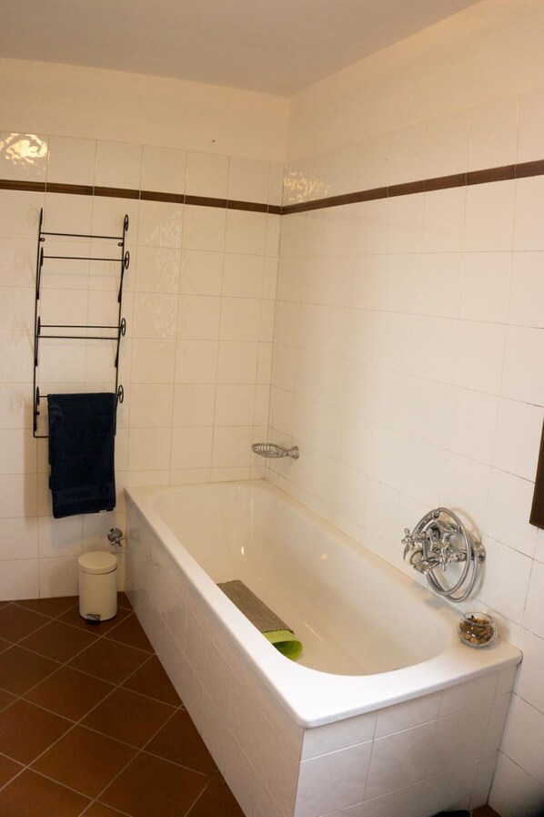 A bathroom with a white bathtub, a towel rack, a small trash bin, and a showerhead. - Nice rustico with see view (Canal D'oro)