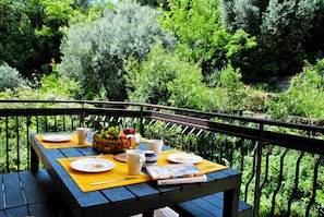 A table set outdoors with plates, cups, and a book, surrounded by lush greenery. - Casa Sofia air Conditioned Flat (Formia)