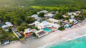 An aerial view of a coastal resort with multiple buildings, a swimming pool, and a beach. - Villa de Lujo en Primera Línea de Playa (San Luis)