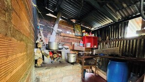 Een landelijke keuken met een bakstenen fornuis, potten en een blauwe ton.