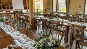 A rustic venue with wooden tables and chairs, white drapes, and string lights. - Chateau Kravín (Kurimany)