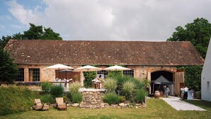 A rustic building with a tiled roof, outdoor seating with umbrellas, and a stone pathway leading to an entrance. - Chateau Kravín (Kurimany)