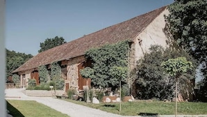 A rustic building with a tiled roof, surrounded by a gravel path and greenery. - Chateau Kravín (Kurimany)
