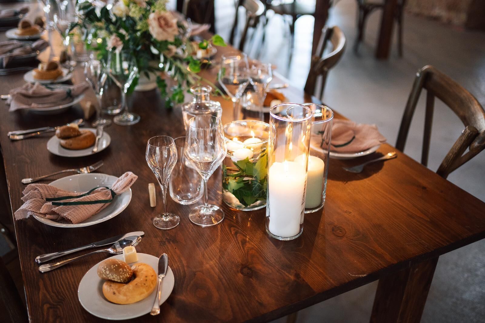 A wooden dining table set with plates, glasses, and candles, suggesting a formal dining setting.