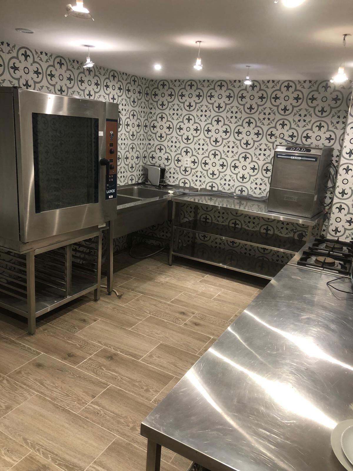 Uma cozinha moderna com eletrodomésticos de aço inoxidável, forno embutido e painel de parede com padrão.