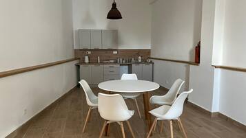 Eine moderne Küche mit weißen Schränken, einer Holzausziehtafel und einem runden Esstisch mit vier weißen Stühlen.