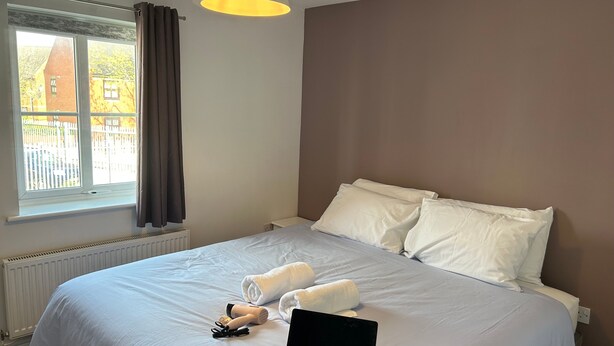 Una habitación de hotel con una cama, una computadora portátil y toallas sobre la cama.