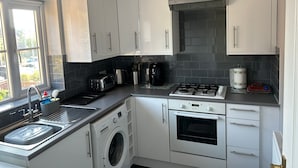 Una cocina moderna con armarios blancos, lavadora integrada, estufa y lavabo.