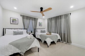 A bedroom with two beds, a ceiling fan, and curtains. - Westchester Garden Su (Miami)