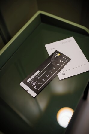 A black and white card with the word "BREAKFAST" on it, placed on a green table. - Welmy Napoli (Naples)