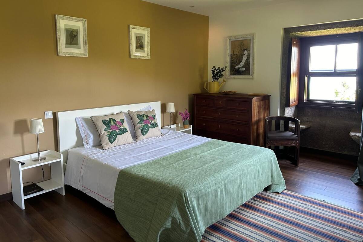 Un dormitorio con cama, mesitas de noche, cómoda y una silla.