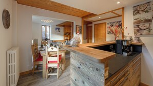 A modern kitchen with wooden accents, a built-in coffee station, and a dining area with red chairs.
