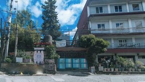 Un bâtiment doté d’une entrée fermée par un portail, d’une enseigne et de plantes en pot.