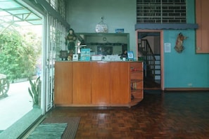 A reception area with a wooden desk, a staircase, and a view of the outdoors. - RedDoorz Hostel @ MRC Residences Baguio (Baguio)