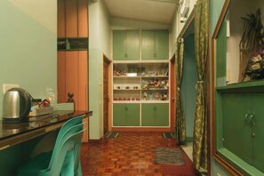 Une cuisine étroite avec un plancher en bois, des armoires vertes et une petite table à manger avec des chaises.