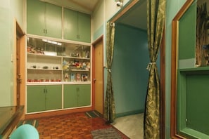A hallway with a green cabinet containing various items, a patterned rug, and a door with a curtain. - RedDoorz Hostel @ MRC Residences Baguio (Baguio)