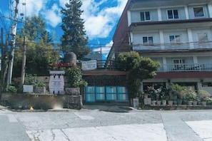Un bâtiment doté d’une entrée fermée par un portail, d’une enseigne et de plantes en pot.