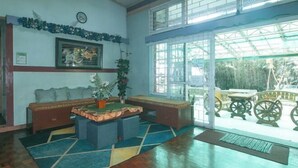 Une pièce avec un plancher en bois, un canapé, une petite table et une fenêtre donnant sur du mobilier d’extérieur.
