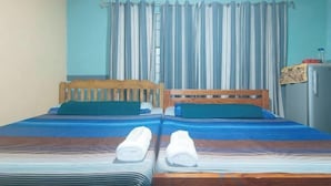 Une chambre avec deux lits, une tête de lit en bois, un rideau à rayures et un petit réfrigérateur.