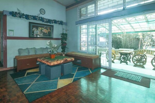 A lobby with a wooden floor, a sofa, a coffee table, a clock, and a large window with a view.